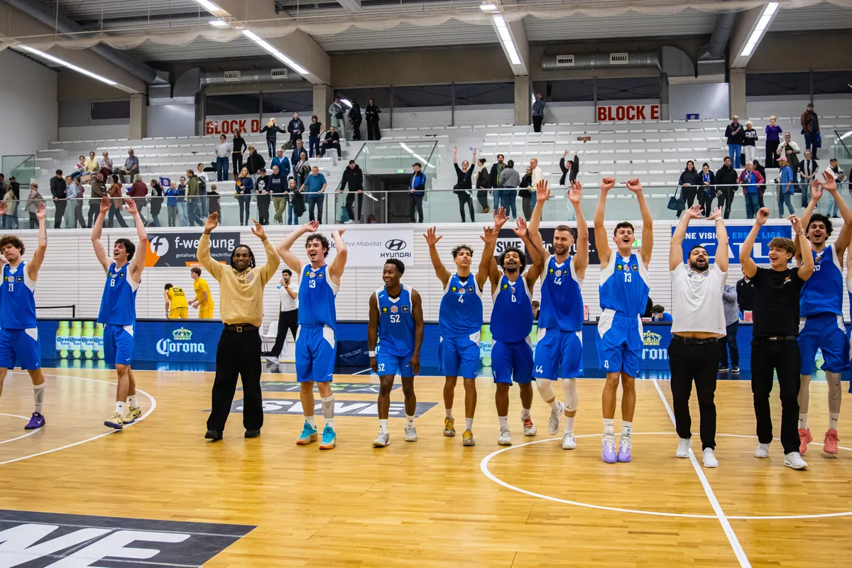 Die Mannschaft der Basketball Löwen Erfurt jubelt mit erhobenen Armen gemeinsam mit den Fans in der Riethsporthalle